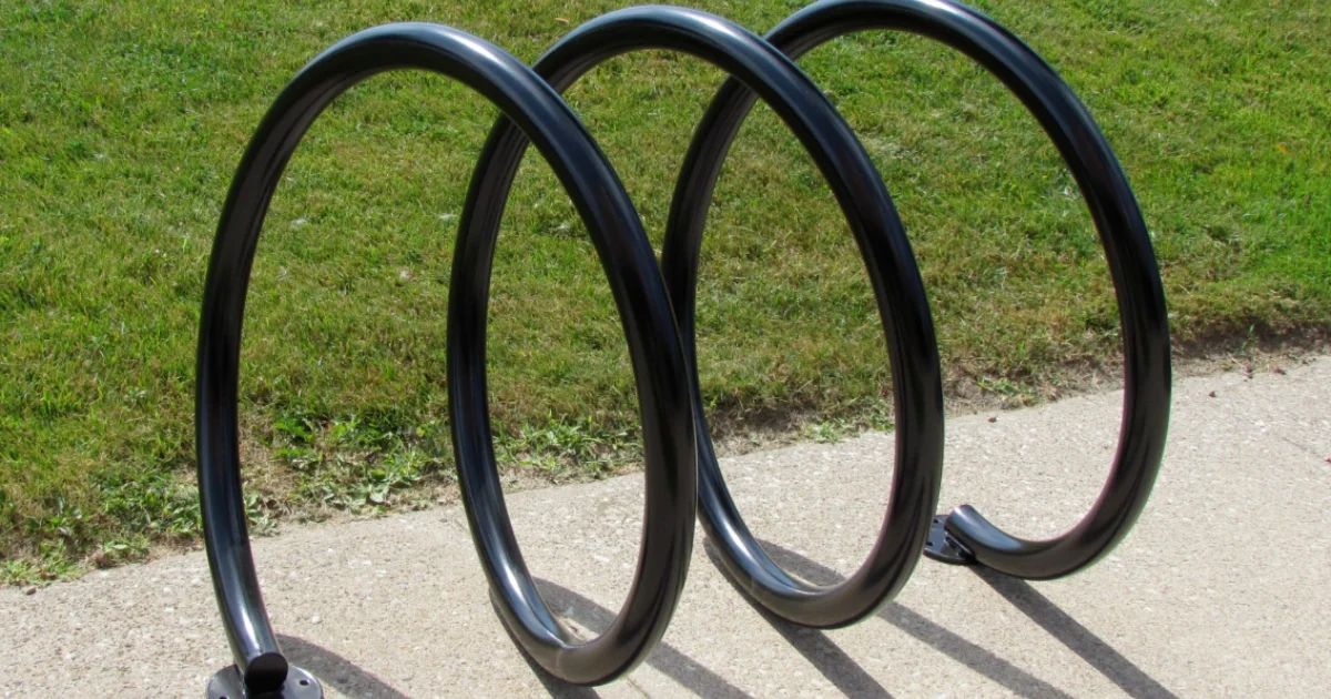 Spiral-shaped black bike rack installed on a sidewalk.